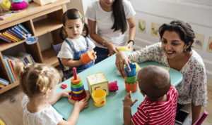 Nursery children playing with teacher in the classroom