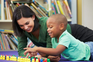 A teacher counting colorful plastic bears with a student