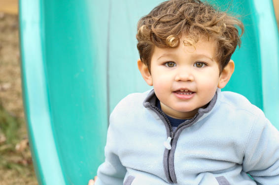 Young boy at the bottom of a green slide